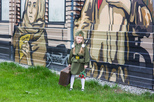 Little girl with retro suitcase in uniform on the Victory Day