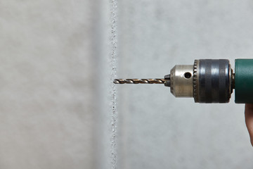 Worker drilling a hole into the wall with an electric drill.