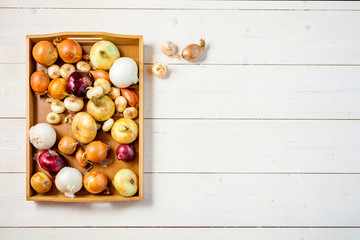 fresh onions on white a wooden table background with copy space for text. wallpaper for grocery shopping and cooking food concept. top view, flat lay