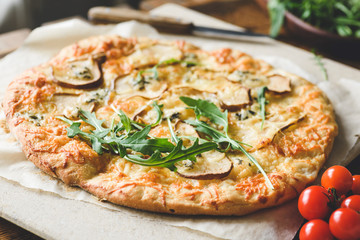 Homemade four cheese pizza with pear and fresh arugula, ruccola. Closeup view, selective focus