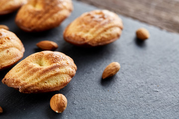 Freshly baked almond cookies on stone board over wooden background, top view, selective focus.