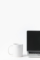 Fototapeta premium close up view of laptop with blank screen and white mug isolated on white