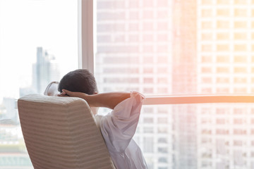 Life-work balance and city living life style concept of business man relaxing, take it easy in office room resting with thoughtful mind thinking of lifestyle quality looking forward to urban scene
