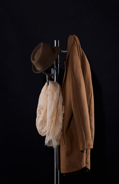 classic coat, hat and scarf hanging on coat rack isolated on black