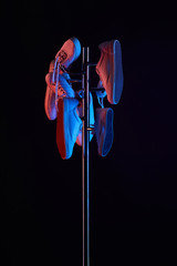 various shoes hanging on coat rack under toned light isolated on black