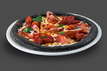Italian pizza with cherry tomatoes, prosciutto and basil isolated over dark background
