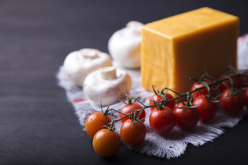  Ingredients - cherry tomatoes, mushrooms and cheese on dark  background