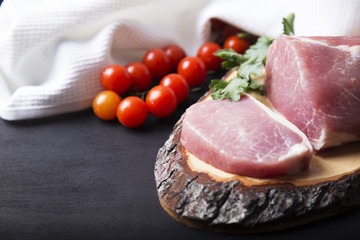 Raw meat  on a cutting board with herbs and vegetables.