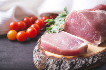 Raw pork sliced meat with tomatoes on wooden board