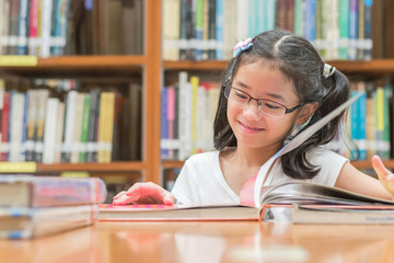 School education and literacy concept with Asian girl kid student learning and reading book in library or classroom