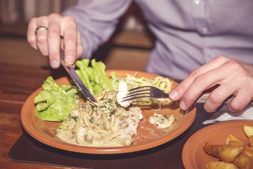 The man has supper at restaurant. Meat with vegetables in sauce