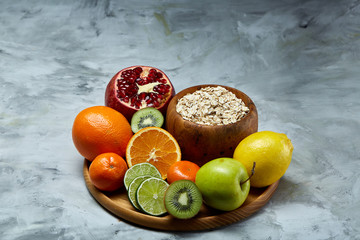 Bowl with oatmeal flakes served with fruits on wooden tray over white background, flat lay, selective focus
