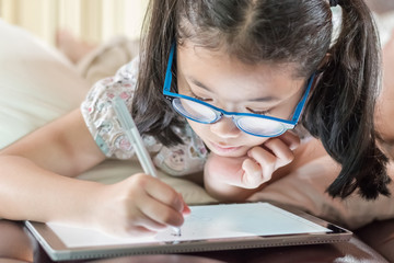 Fototapeta na wymiar Asian school child girl using smart tablet device digital technology drawing on innovative touchscreen surface