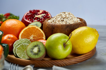 Obraz na płótnie Canvas Bowl with oatmeal flakes served with fruits on wooden tray over white background, flat lay, selective focus