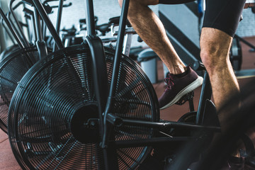 Cropped image of sportsman doing workout on exercise bike in sports center