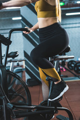 Fototapeta na wymiar Cropped image of sportswoman doing workout on exercise bike in sports center