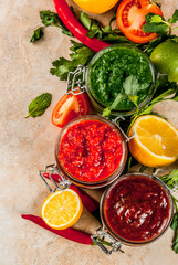 Indian traditional food, Set of three chutney for Chaat and Sev Puri - sweet date-tamarind, cilantro-mint green and red chilli garlic, On beige stone background, copy space top view
