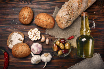 Fototapeta premium Olives in oil with spices in glass vase and bread on table