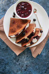 Chocolate crepes (blinis) with sour cream sauce and black currants on a white plate. Blue stone...