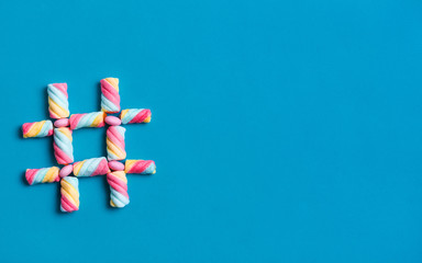 Hash tag symbol made from sweets isolated on blue background with copy space for text.