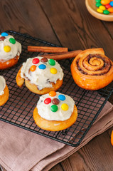 Classic cinnamon rolls - cinnabons with cream cheese frosting with smarties. Wooden background.