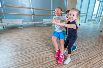 Children and recreation, group of happy multiethnic school kids playing tug-of-war with rope in gym