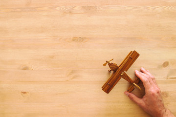 top view photo of man's hand holding toy airplane over wooden background.