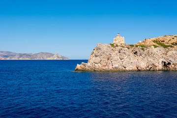 Fototapeta na wymiar The lighthouse on cliff and blue sea. Ios island. Greece.