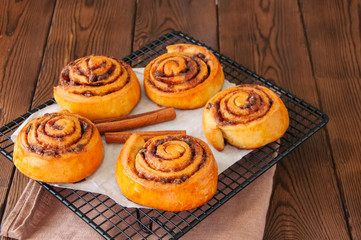 Classic cinnamon rolls - cinnabons on a wire rack. Wooden background.