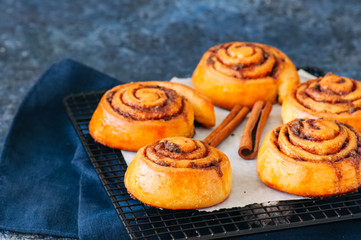 Classic cinnamon rolls - cinnabons on a wire rack. Blue stone background.