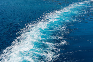 Background of water trail foaming behind a ferry boat.