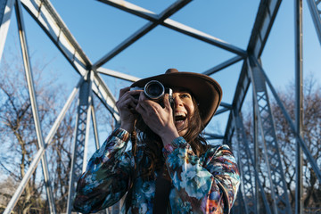Smiling young woman using a camera to take photo.