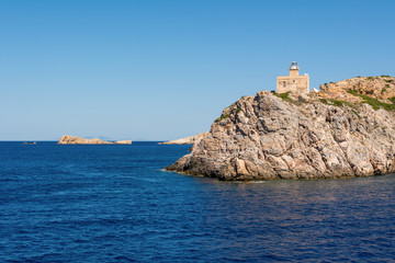 Fototapeta na wymiar The lighthouse harbor on rocks by sea on Ios island. Greece.