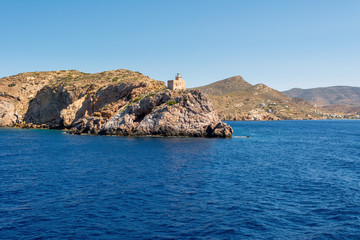 Fototapeta na wymiar The lighthouse harbor on rocks by sea on Ios island. Greece.