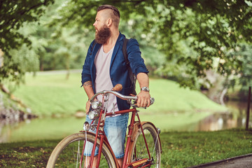 Traveler dressed in casual clothes with a backpack, relaxing in a city park after riding on a retro bicycle.