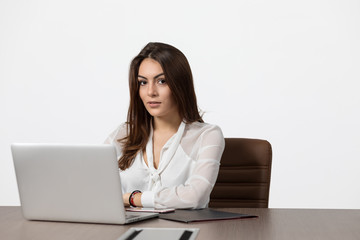 Beautiful young business woman looking at camera and smiling while working at laptop in office. Woman against white background.