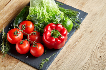 Artistic still life of assorted fresh vegetables and herbs on rustic wooden background, top view, selective focus.