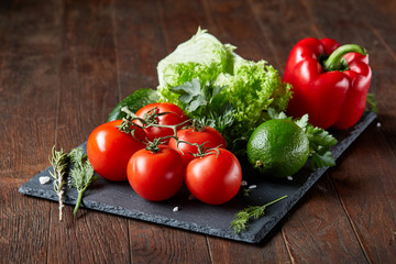 Artistic still life of assorted fresh vegetables and herbs on rustic wooden background, top view, selective focus.