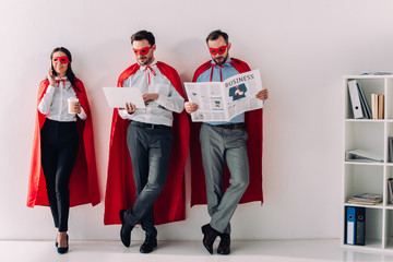 super businesspeople with newspaper, laptop and smartphone in office