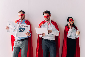 super businesspeople with newspaper, laptop and smartphone isolated on white