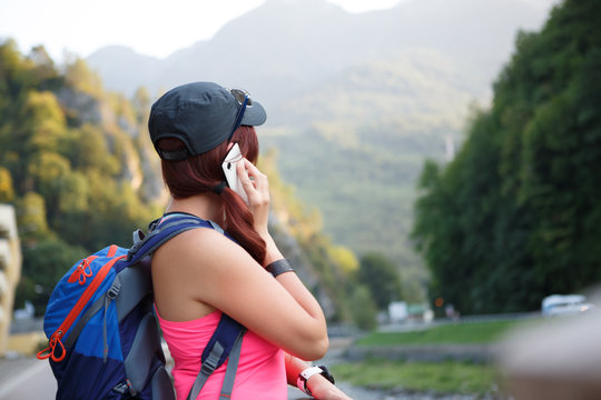 Image from back of tourist girl talking on smartphone