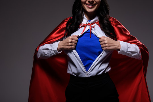 cropped image of super businesswoman in red cape showing blue shirt isolated on black