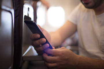 Businessman in airplane using smart phone.