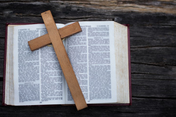 The wooden cross over opened bible on wooden table