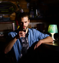 Guy at bar counter drinks glass of shot or liqueur.