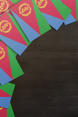 Naklejka premium Eritrea small flags framing a wood texture background with copy space