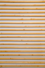 Wooden horizontal slats batten on a light gray wall background. Interior detail, texture, background. The concept of minimalism and Scandinavian style in the interior. Copy space