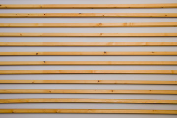 Wooden horizontal slats batten on a light gray wall background. Interior detail, texture, background. The concept of minimalism and Scandinavian style in the interior. Copy space