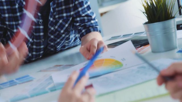 A modern young man participates in a discussion with colleagues. Young and bright contemporary small creative business. Casual young people in architecture or marketing agency company.