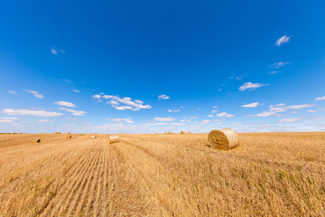 Wheat field after harvest with straw bales at sunset
